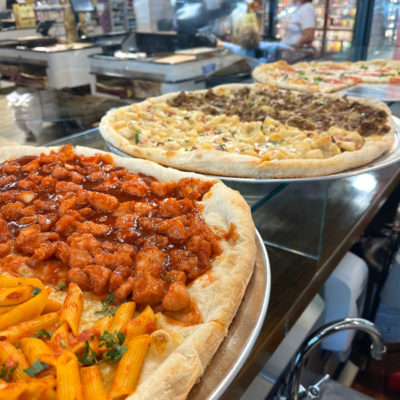 Some of the pizzas in the display case at Pizza N' Bites - DeCicco & Sons